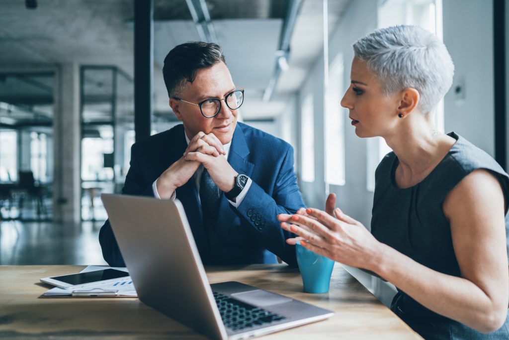 Woman and man having discussion while looking at information on a laptop