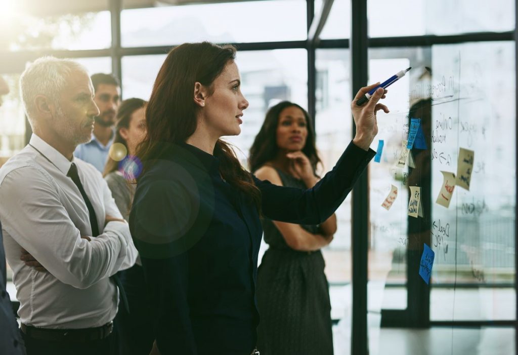 Woman leading white-boarding exercise with colleagues 