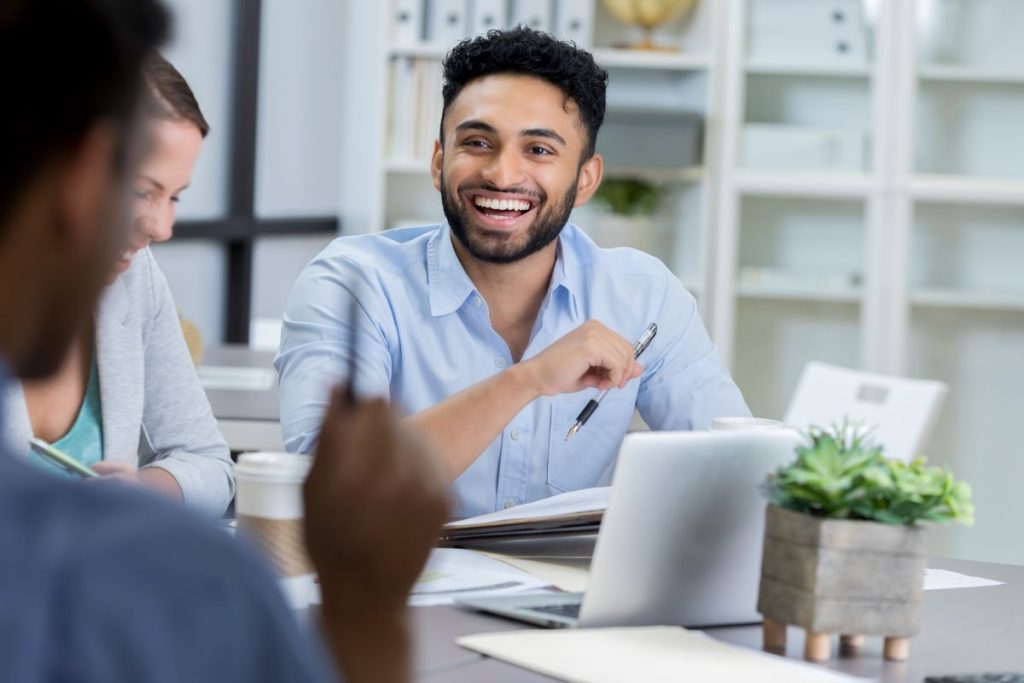 Man laughing while talking to colleagues