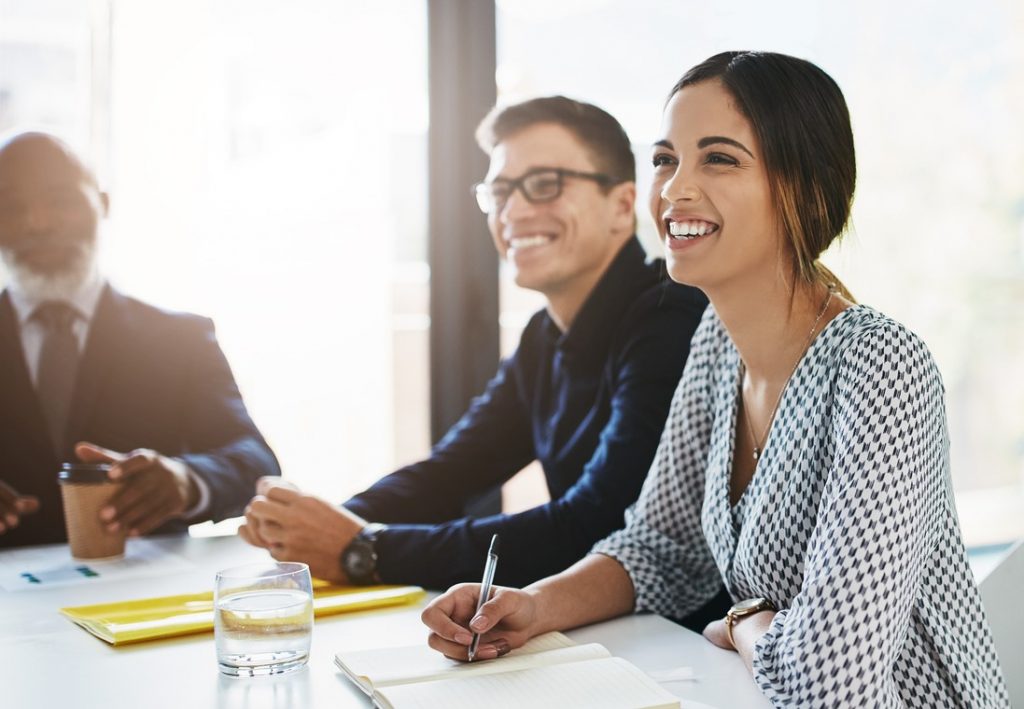 Colleagues smiling while listening to a presentation